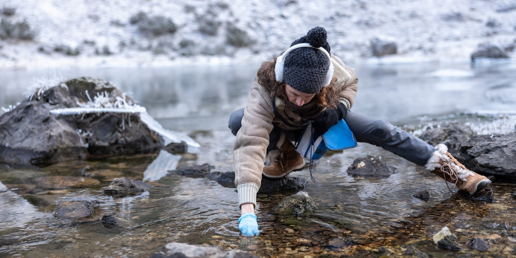 Woman Biologist Collecting Environment Samples from a Mountain Lake in Winter